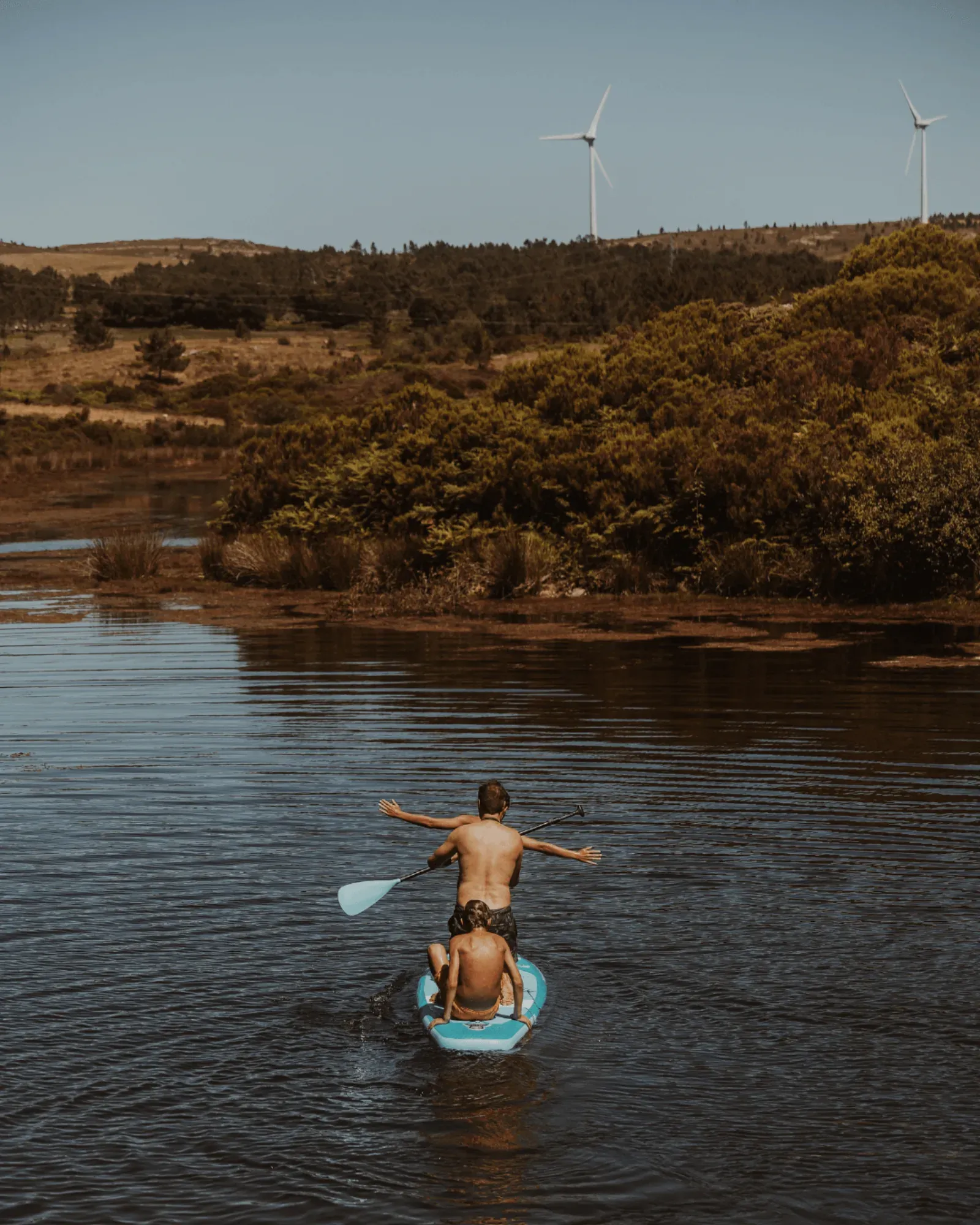 Mãe e criança numa prancha de paddle no rio